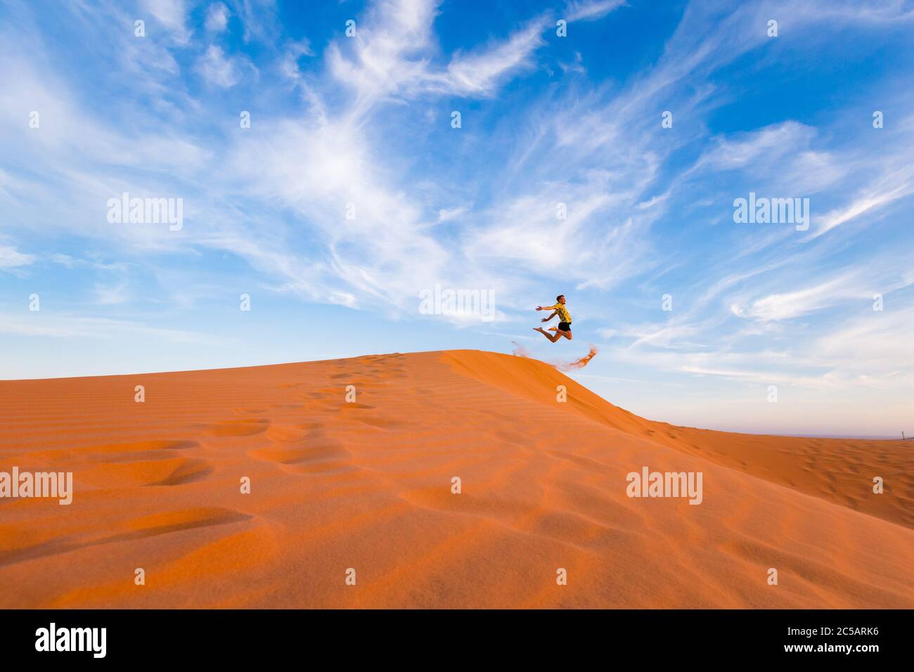 Young handsome man having fun on Red sand dunes in Mui Ne, Phan Tiet ...