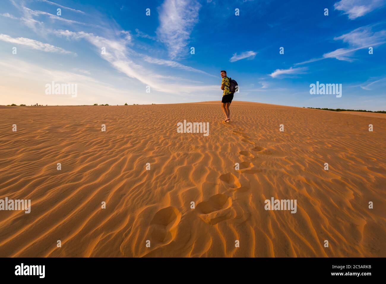 Young handsome man having fun on Red sand dunes in Mui Ne, Phan Tiet ...