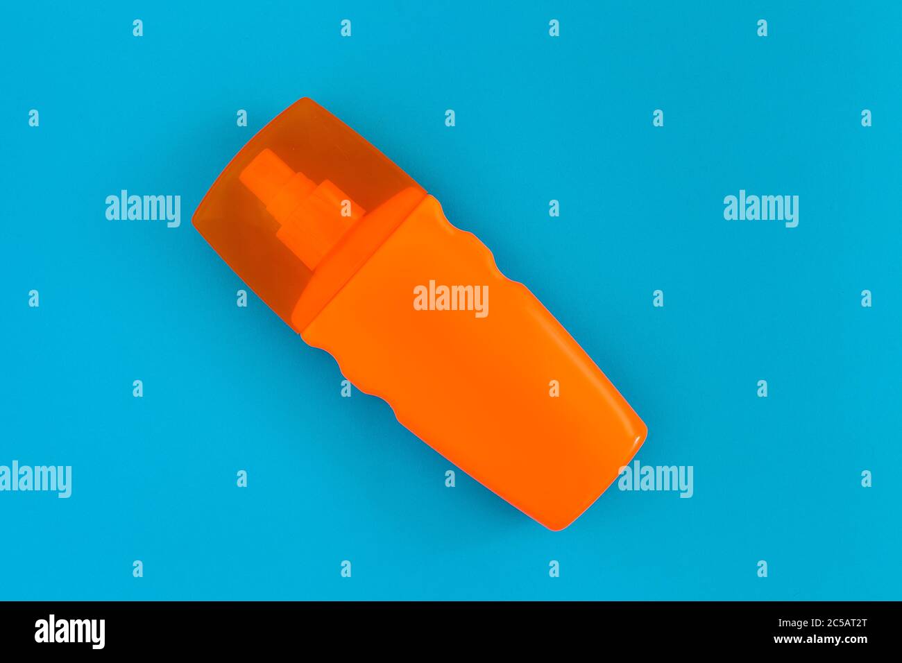 sunscreen for healthy skin care in an orange bottle with a spray bottle lies across on a blue background top view with place for text, nobody. Stock Photo