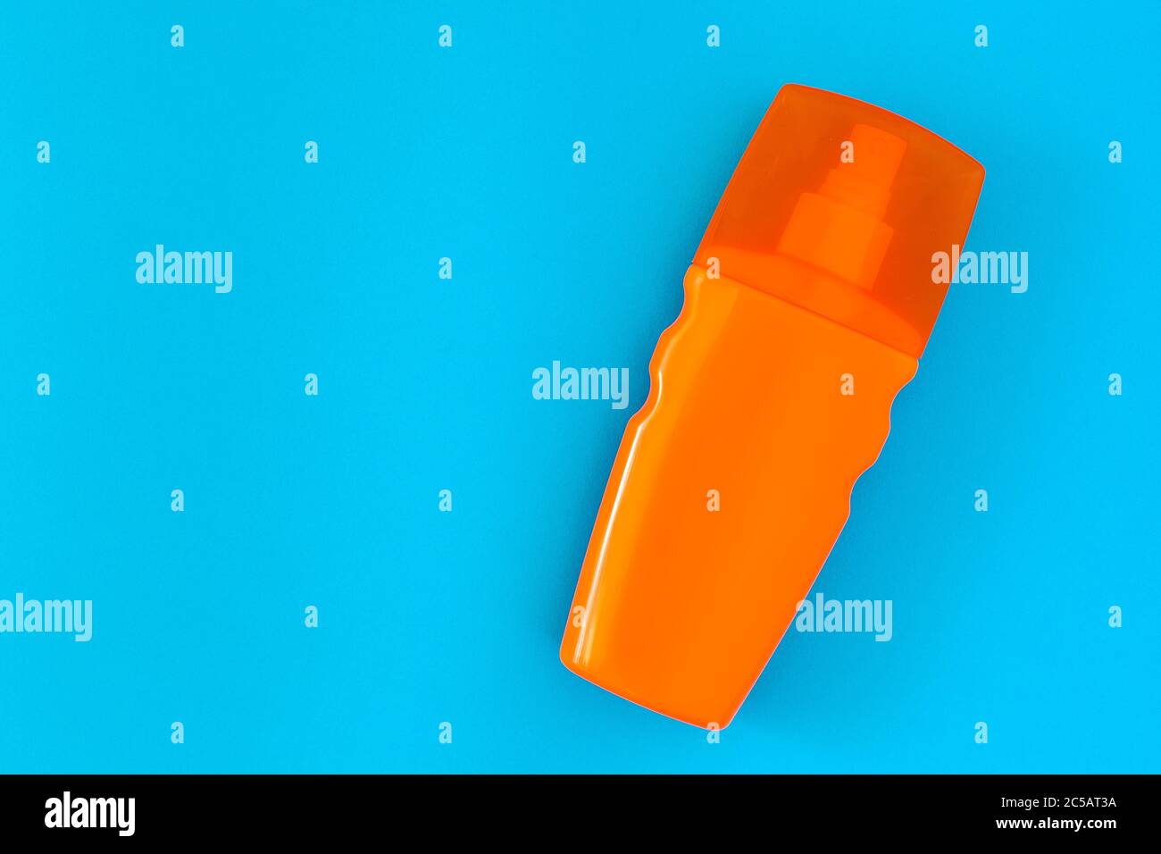 sunscreen in an orange bottle with a spray bottle and a transparent cap lies on a blue background top view with place for text. Stock Photo