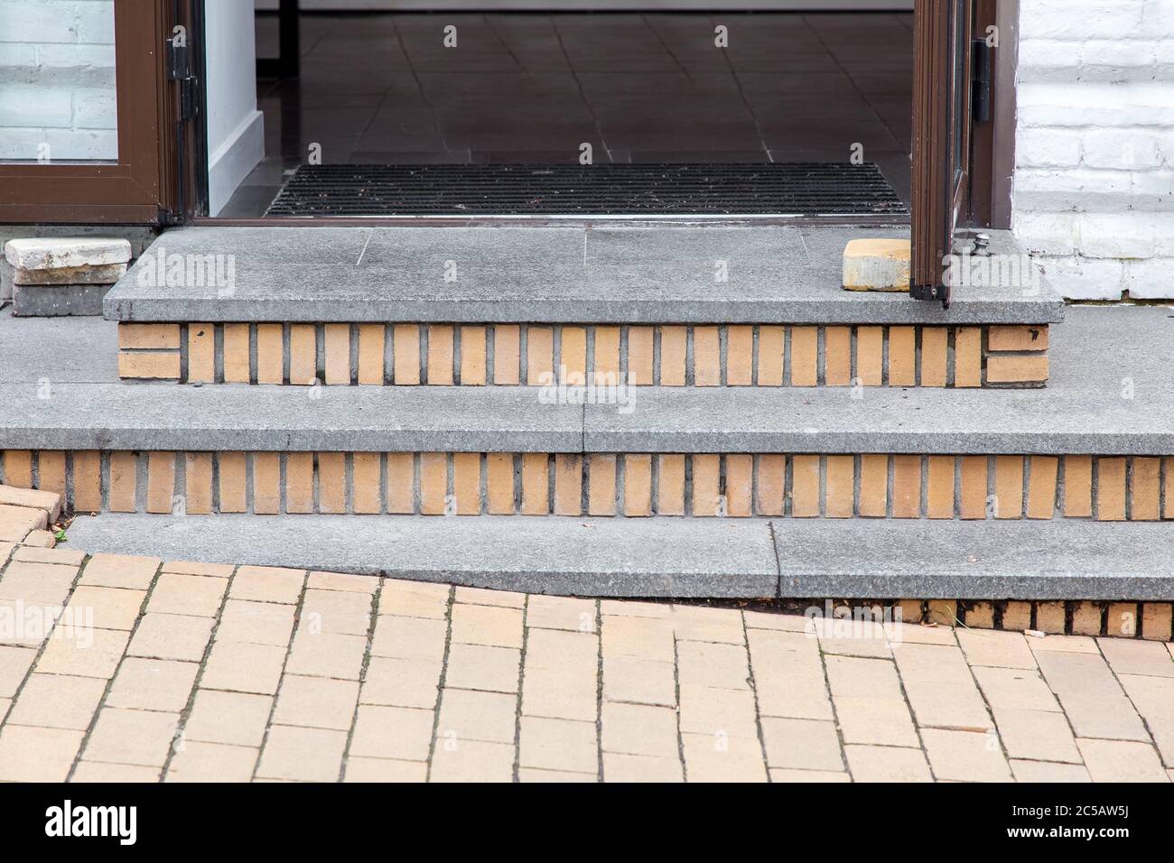 gray granite steps of a brick threshold at the open entrance door to the  building from the street with stone paving slabs, closeup of architectural  de Stock Photo - Alamy