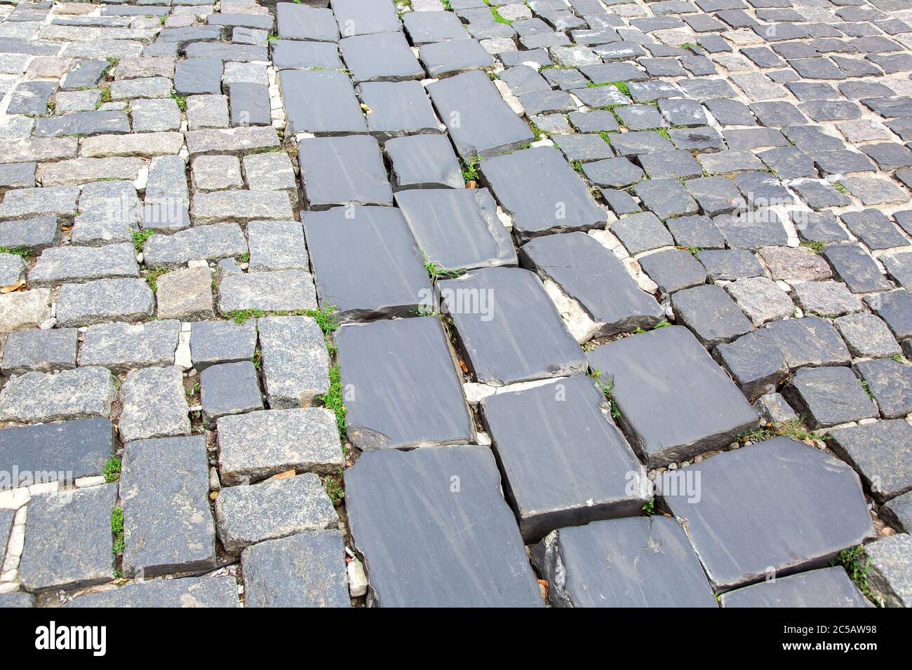hardscape sett cobblestone old roadway on historical europe city, close up footpath texture nobody. Stock Photo