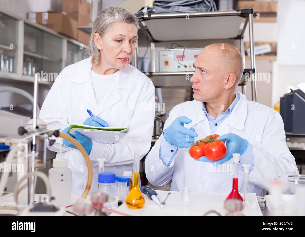 Scientists Comparing Notes Scientific researching in laboratory. Two scientists taking notes while ...