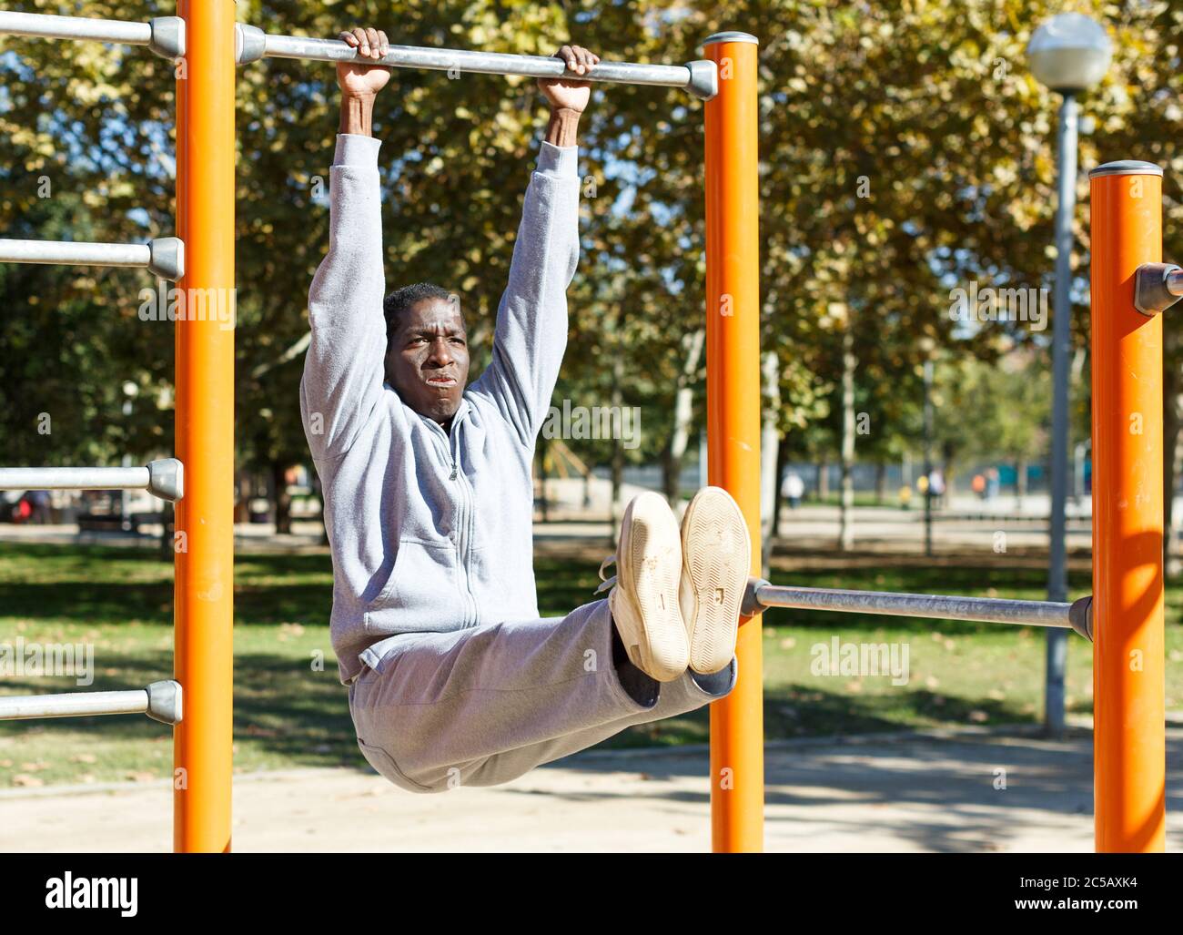 Athletic young male training different exercises at chin up bar in