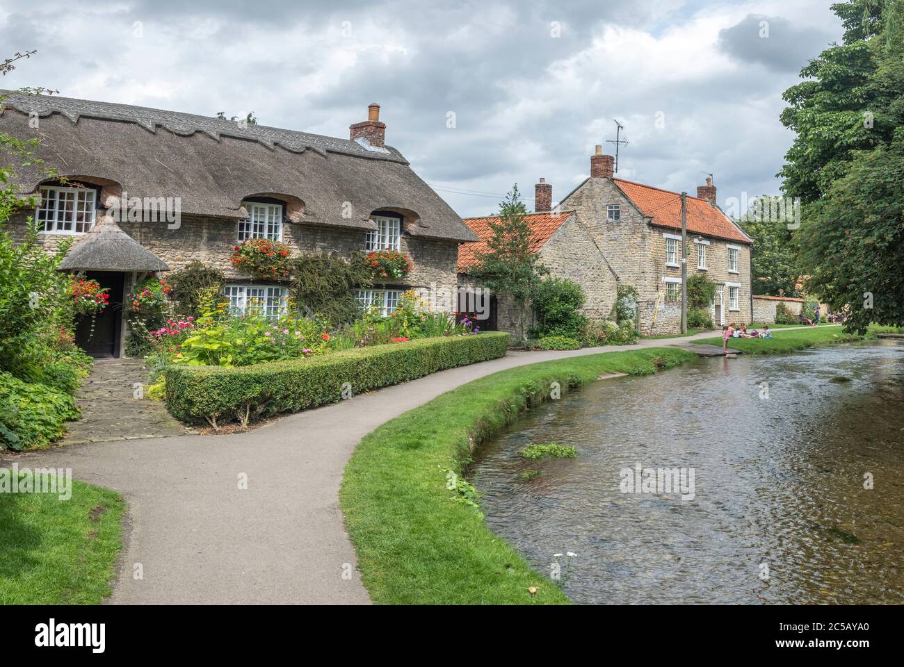 A well photographed thatched cottage next to Thornton Beck in the small North Yorkshire village of Thornton le Dale Stock Photo