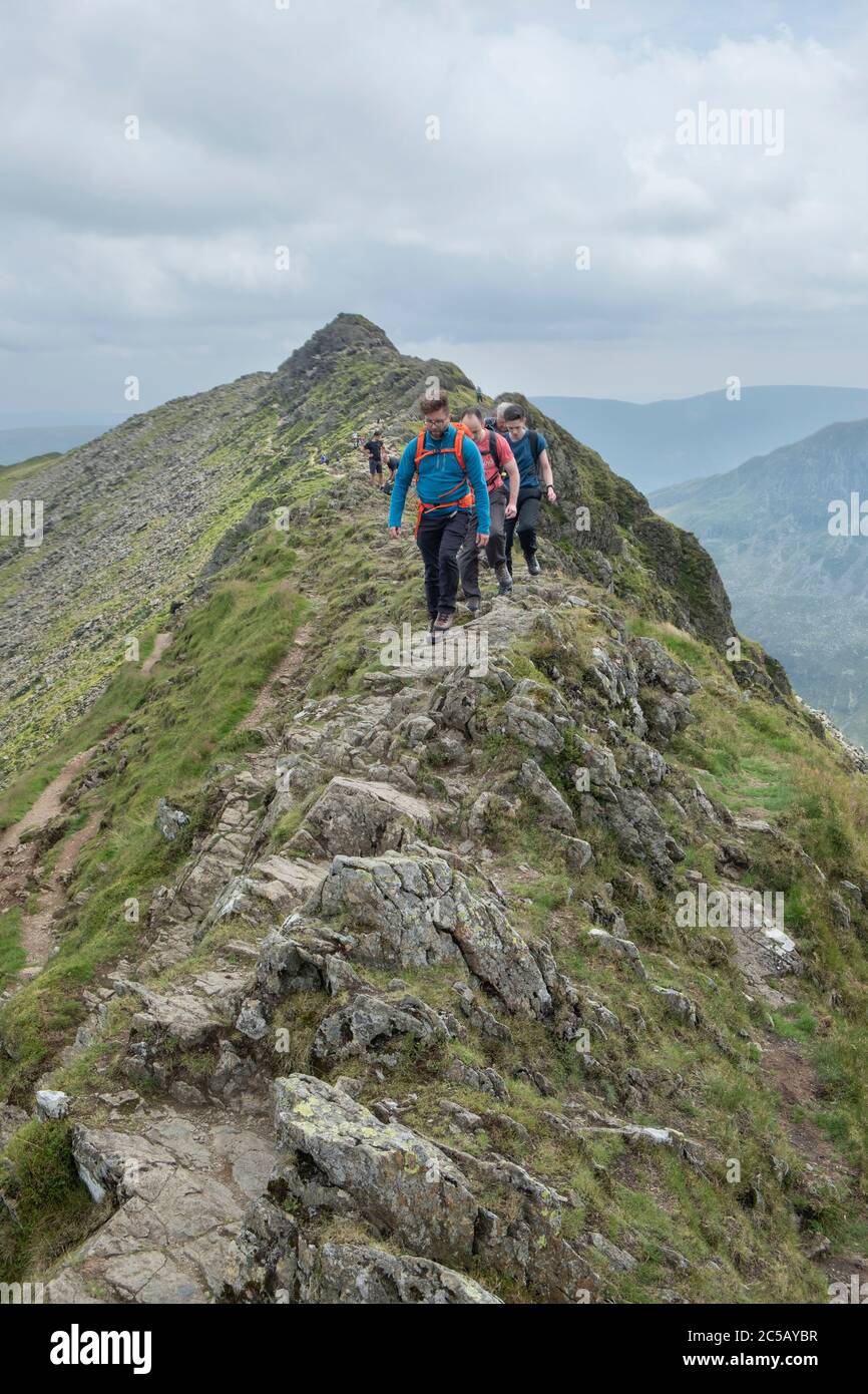 Walkers scramble over rocks on the ridge of striding edge in the lake district Stock Photo