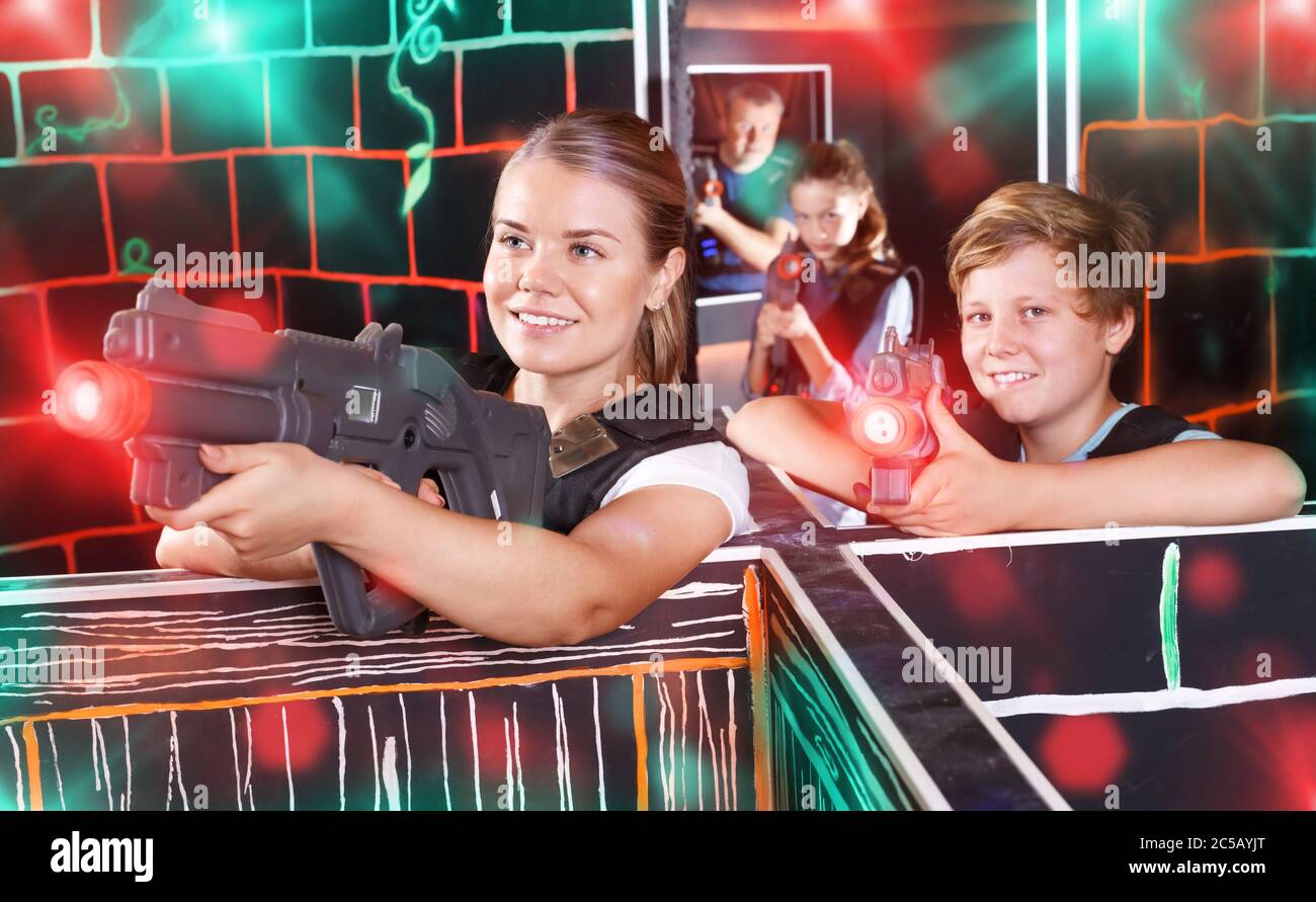 Modern young mother and teen son with a laser pistols playing laser tag