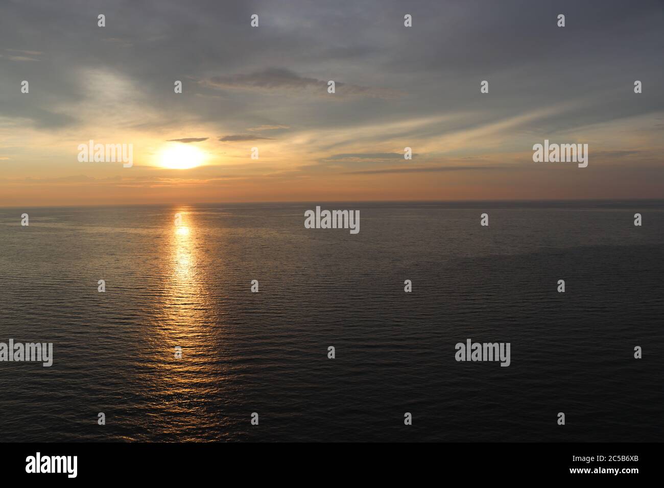 sunset over water with cloudy skys Stock Photo - Alamy