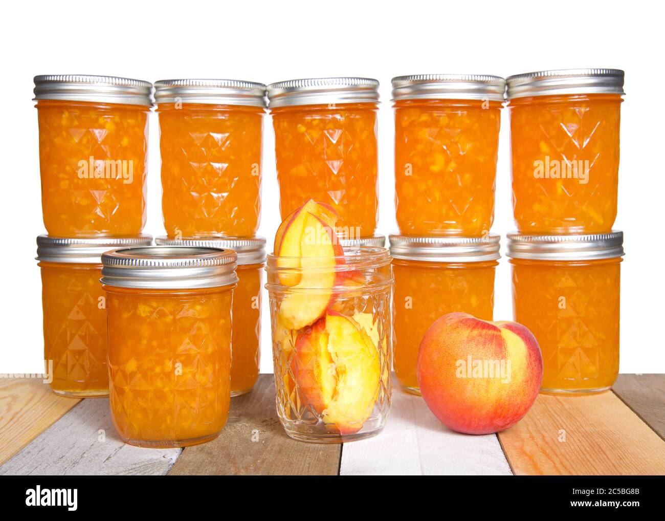 Fresh sliced peaches in an open mason jar with whole peach on table