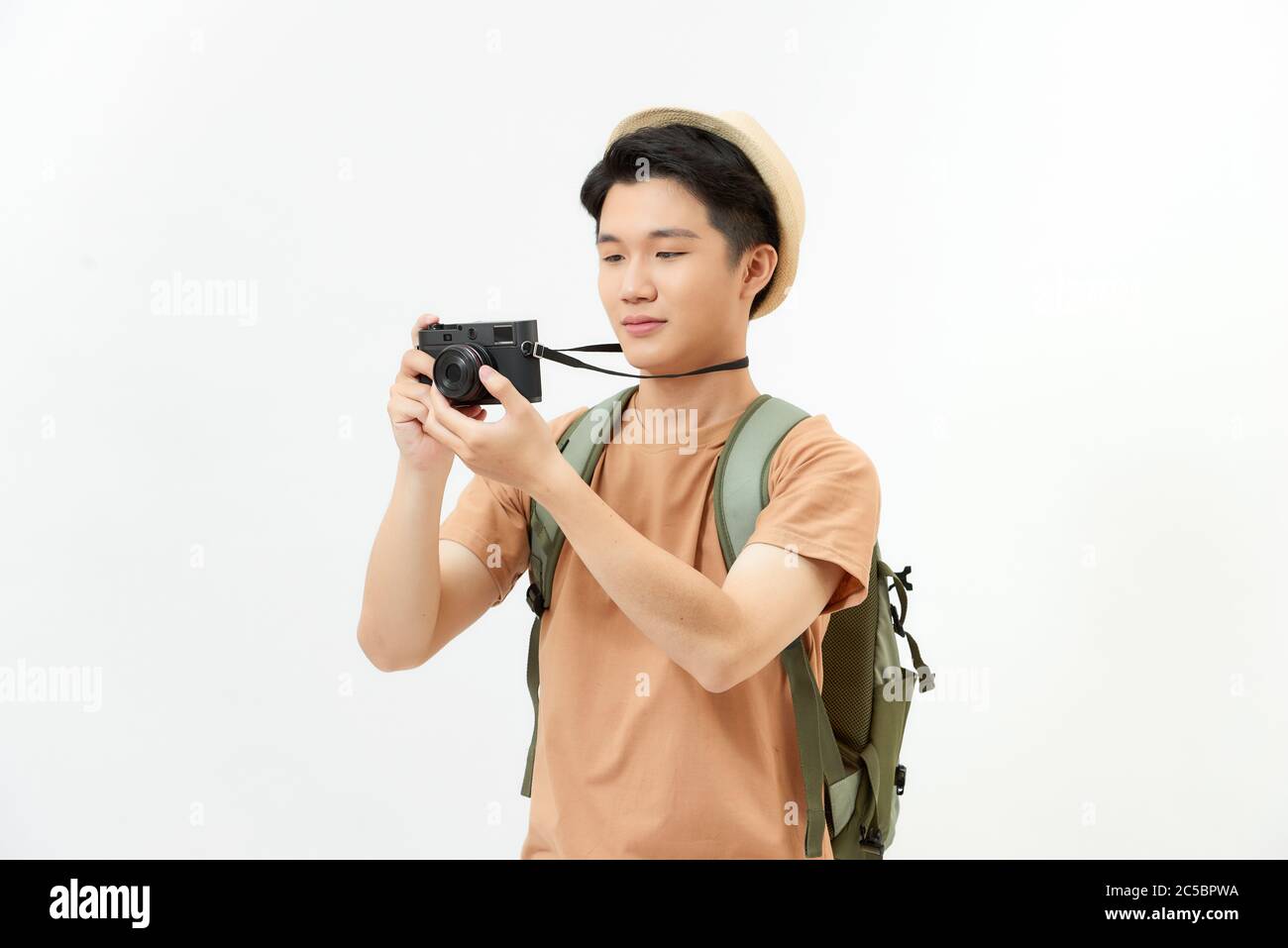 Traveler and photographer. Studio portrait of handsome young man holding photocamera taking photo. Stock Photo