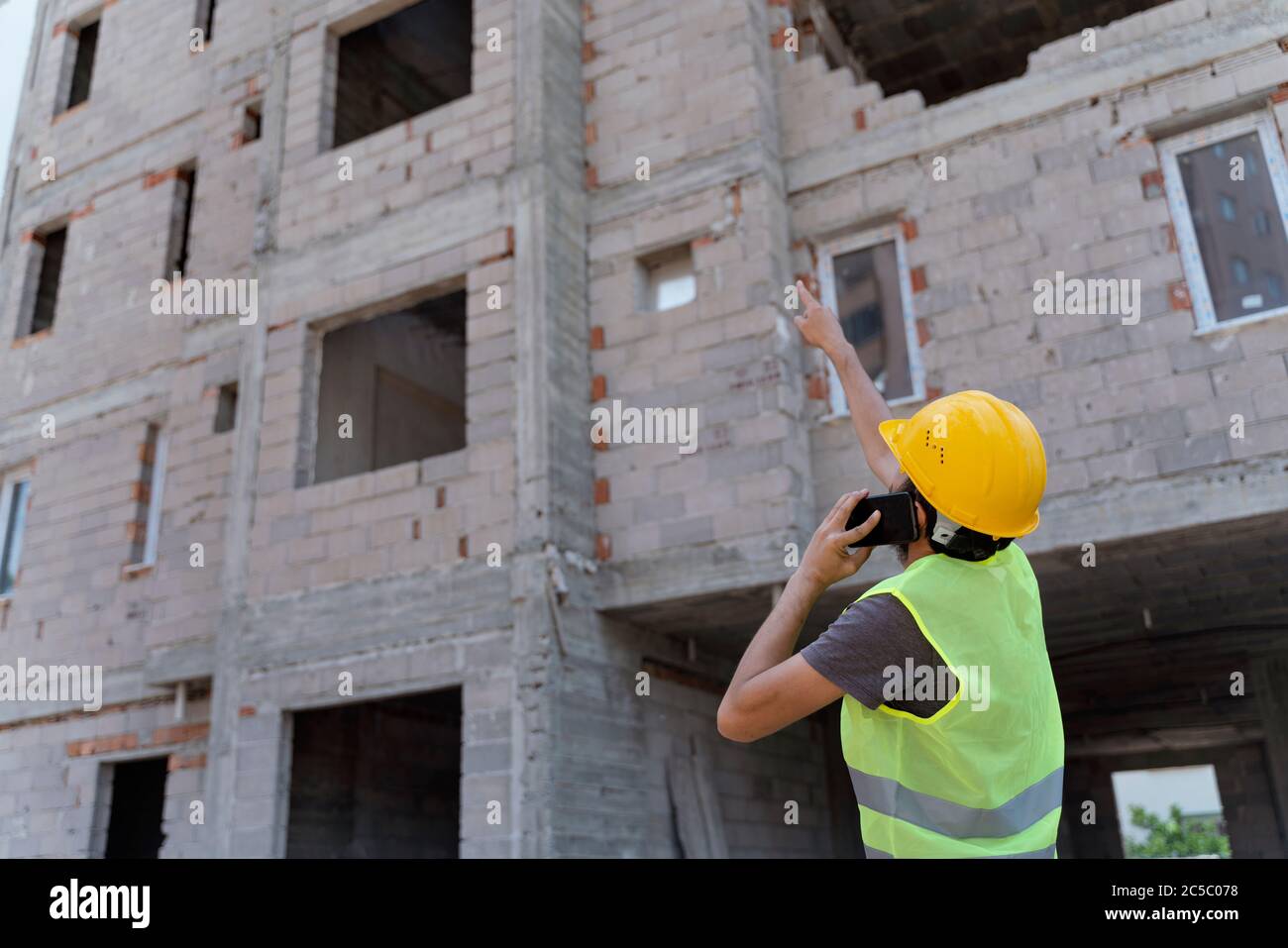 Site manager with safety vest talking mobile phone under construction Stock Photo