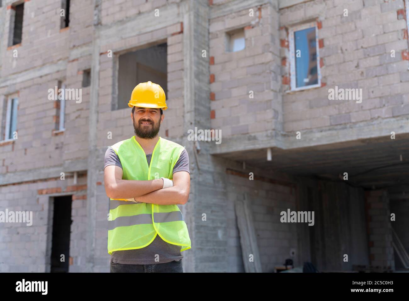 Construction worker looking at camera with hardhat in construction site background Stock Photo