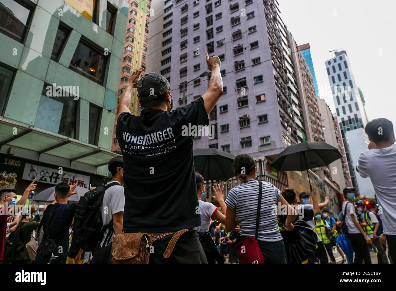 A man wearing a 'Hongkonger' shirt makes a 'Five Demands, Not One Less.' gesture during demonstrations. The National Security Law is a piece of legislation introduced by Beijing for Hong Kong. Composed of 66 articles that were in complete secrecy until after it was passed, it criminalizes any acts of secession, subversion, terrorism and collusion with foreign or external forces with a maximum sentence of life in prison. The law officially came into effect at 11pm on June 30, 2020 - the evening before the 23rd anniversary of Hong Kong's handover from Britain back to China. On July 1, thousands Stock Photo