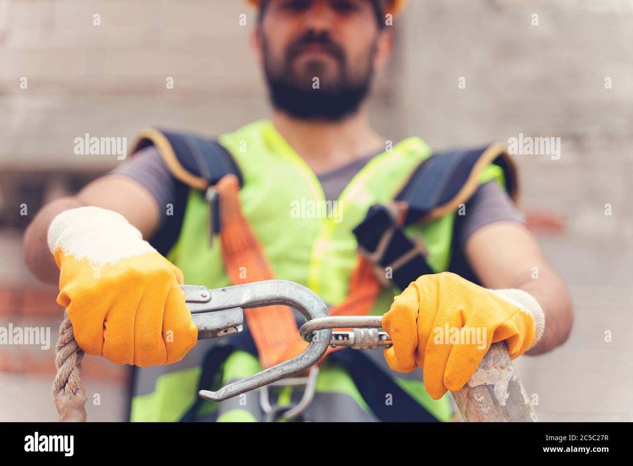 Working at height equipment. Fall arrestor device for worker with double hooks for safety body harness on selective focus. Construction as a backgroun Stock Photo