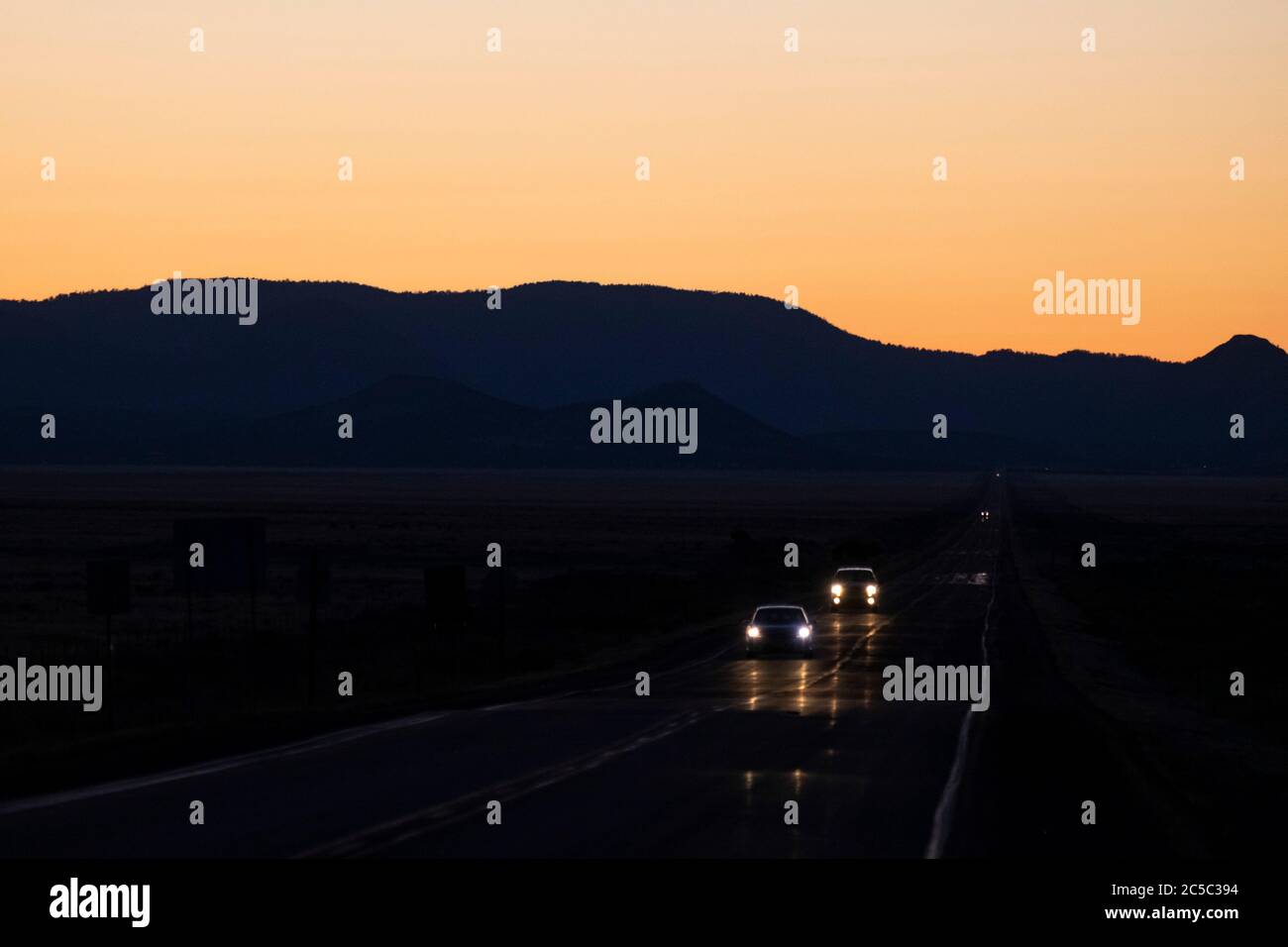 Headlights of cars on a lonely stretch or road in the desert of New Mexico in the evening Stock Photo