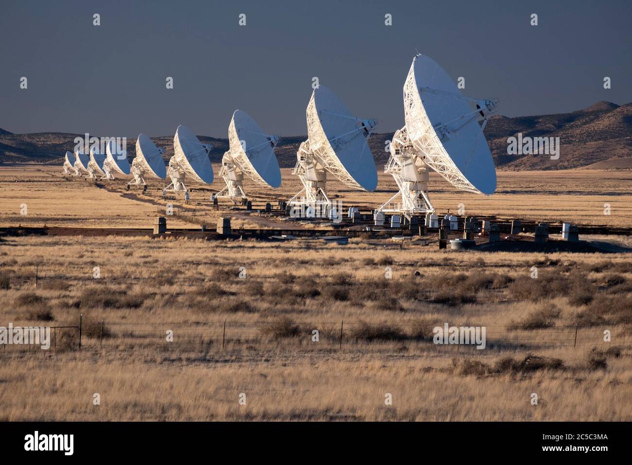 Row of radio telescope dishes all lined up at the Very Large Array (VLA) in the high desert of New Mexico Stock Photo