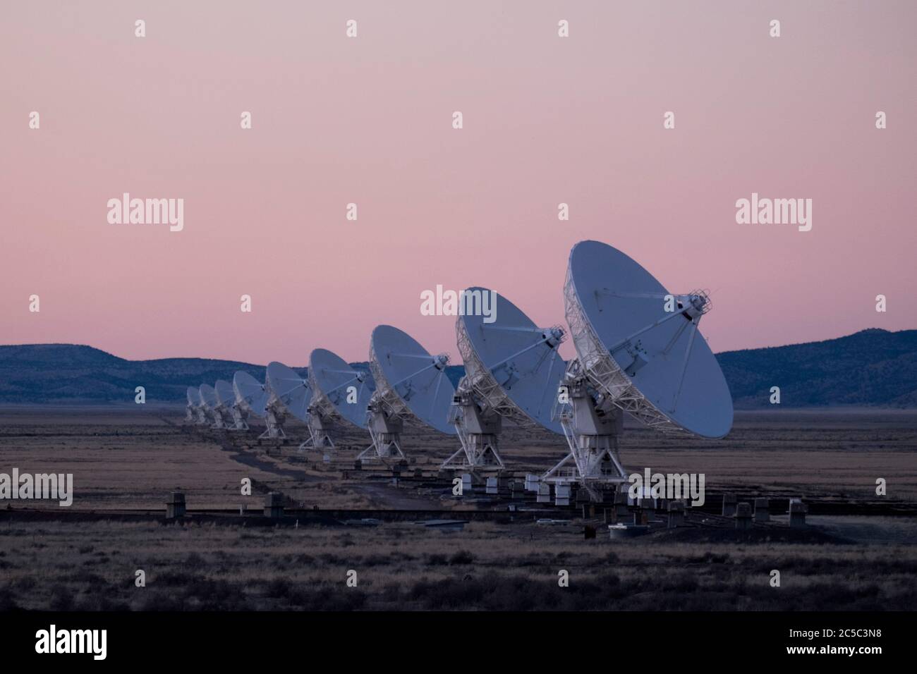 Radio astronomy dishes in pink dusk light as night falls on the Very Large Array (VLA) in New Mexico Stock Photo