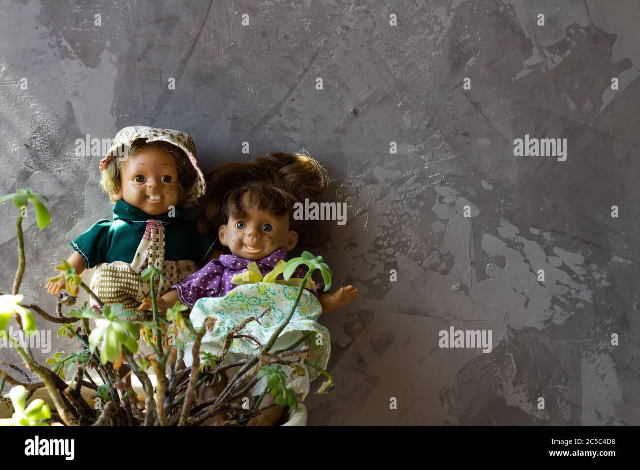 Old, scary, ugly dolls in front of concrete wall. Stock Photo