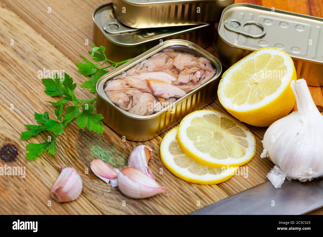 Tin can of natural chopped tuna belly in oil on wooden background with