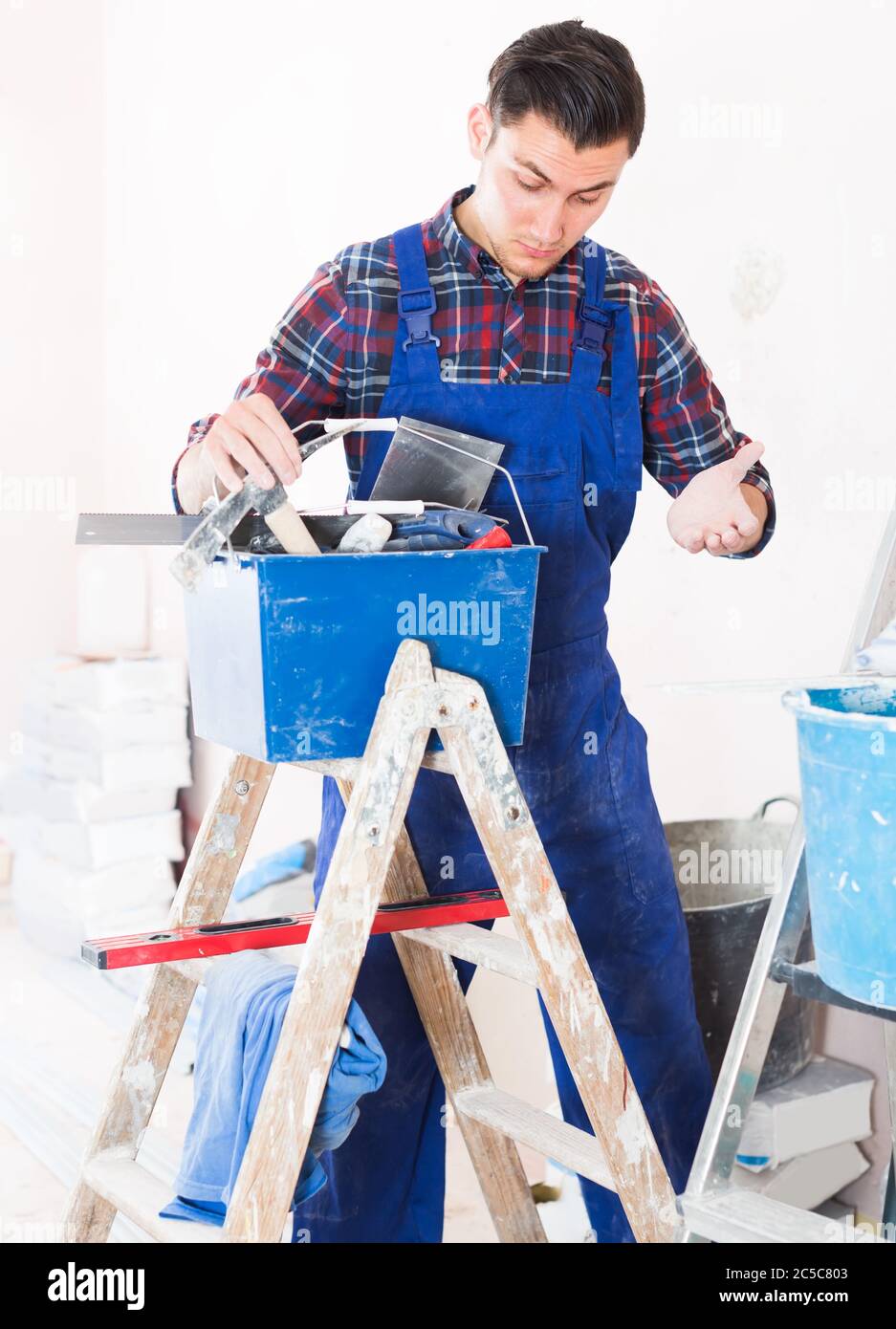 Young attentive builder handyman choosing necessary tool in toolbox Stock Photo