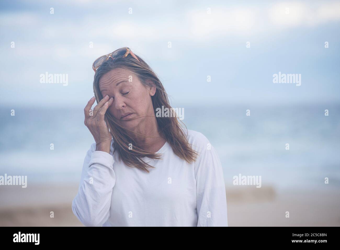 Portrait attractive mature woman with closed eyes, stressed, tired, thoughtful suffering from menopause, blurred background outdoor, copy space. Stock Photo