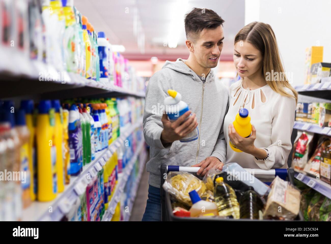 Young couple making purchases together, buying household chemicals in shop Stock Photo