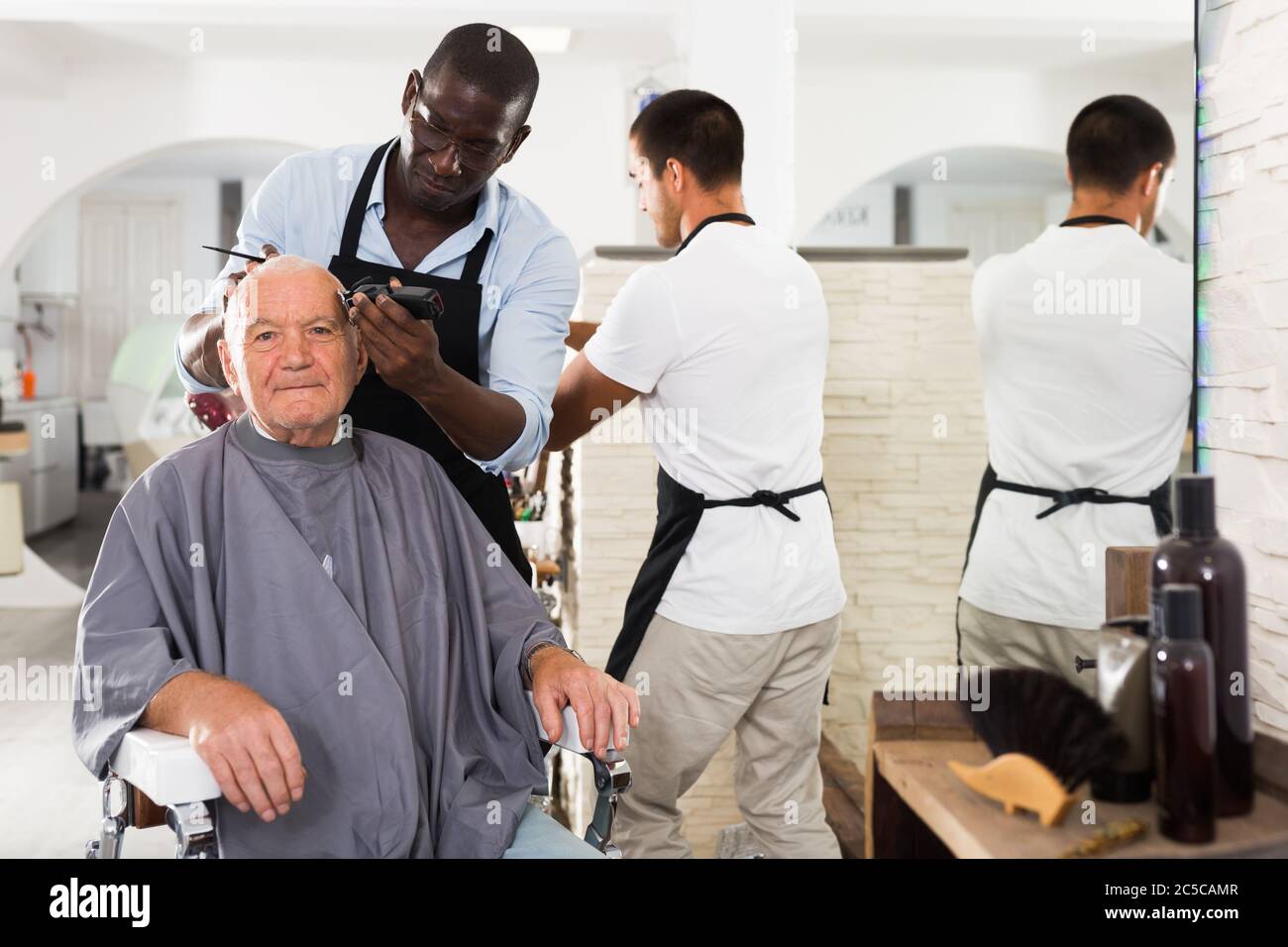 AfricanAmerican hairdresser doing styling for grayhaired man with