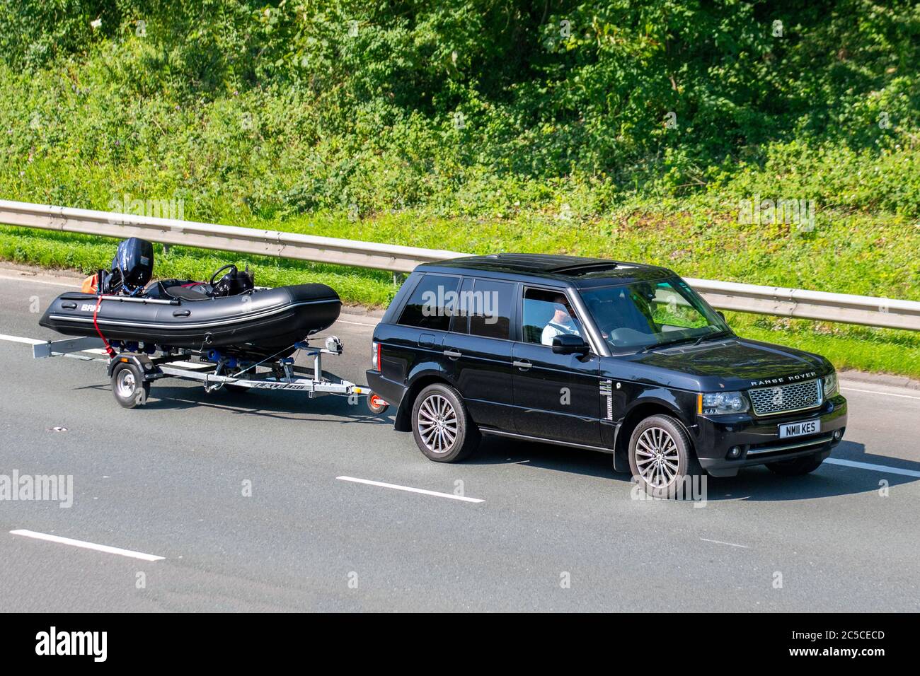 2011 black Land Rover Range Rover Vogue se ; Vehicular traffic moving vehicles, cars towing boat trailer, driving vehicle on UK roads, motors towed BRIG rigid inflatable boats, motoring on the M6 motorway highway network. Stock Photo