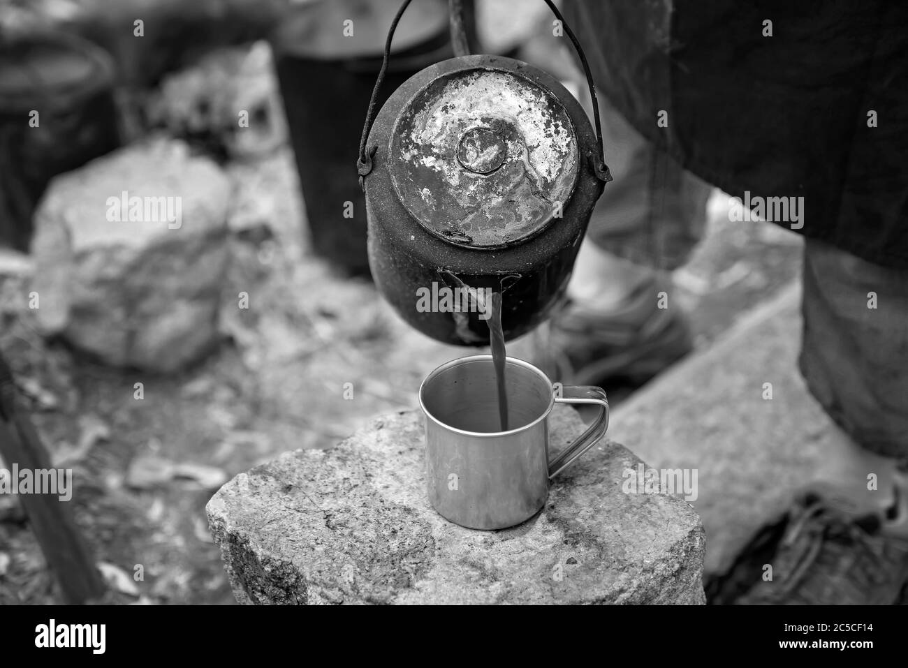 Coffee being poured from a billy at a campfire guest bush breakfast at an outback Australian tourist resort in a volcanic national park Stock Photo