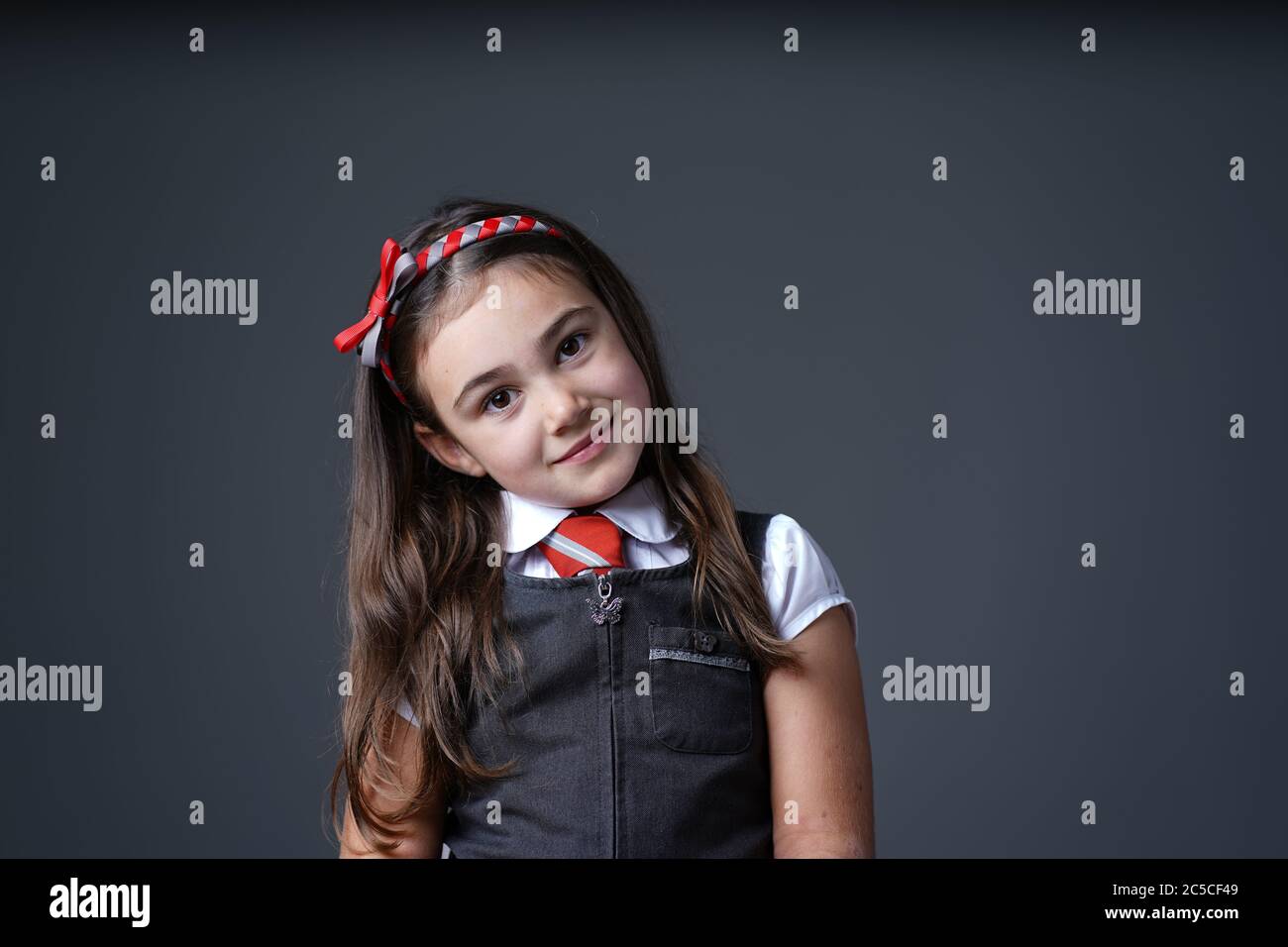 primary school elementary girl child wearing school uniform with grey and red colours color Stock Photo