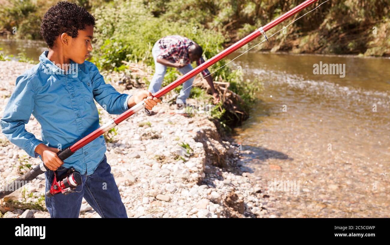 Little African boy fishing with his father and pulling fish Stock Photo