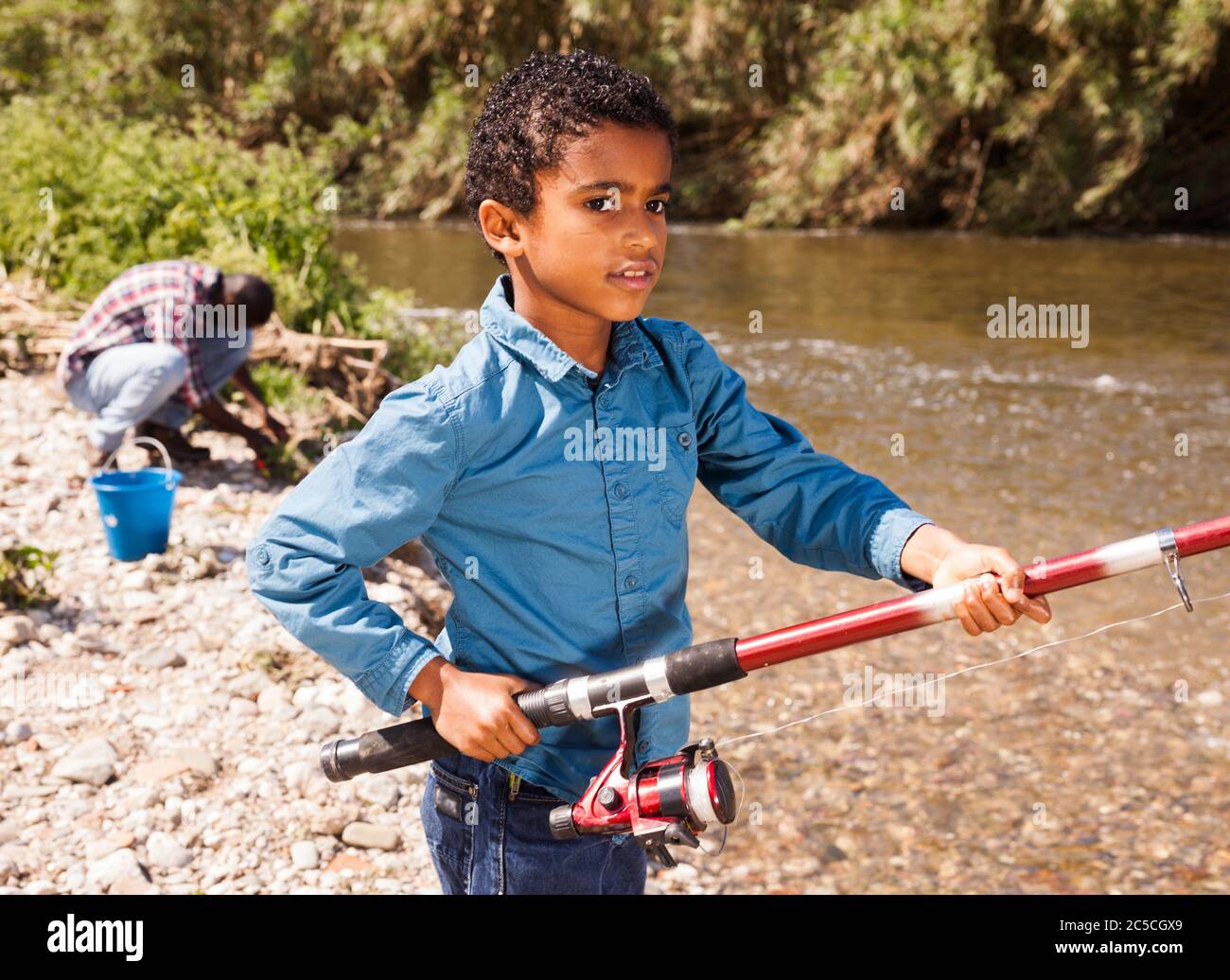 Little African boy fishing with his father and pulling fish Stock Photo