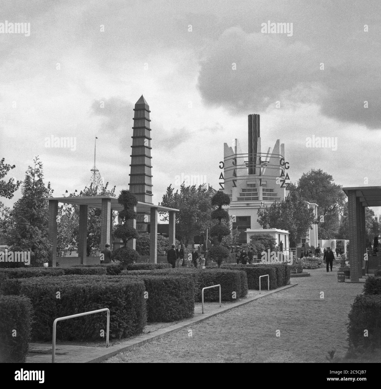 A view of the 1937 Expo (World's Fair or Exposition) held in Paris, France – here people are strolling in the 'Sections des Jardins', gardens alongside the River Seine. In the background is a pavilion for the French power company Gaz. Stock Photo