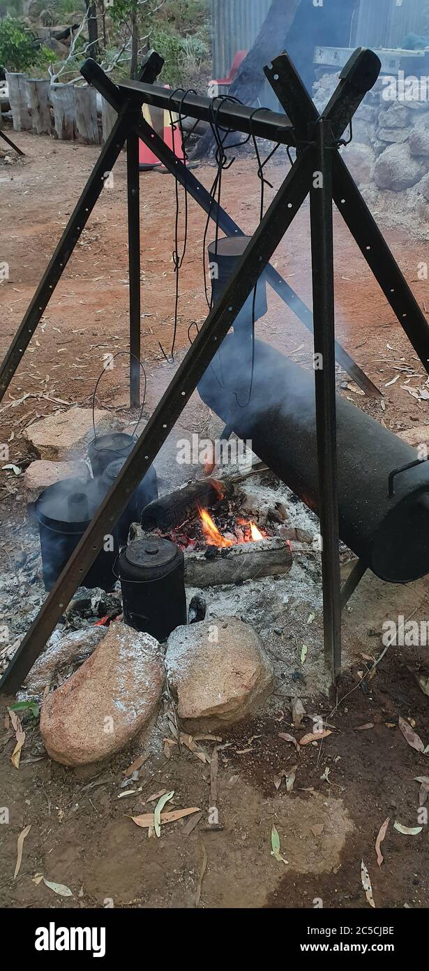 Water boiling for billy tea over campfire hot coals at an Australian bush breakfast at an outback tourist resort Stock Photo