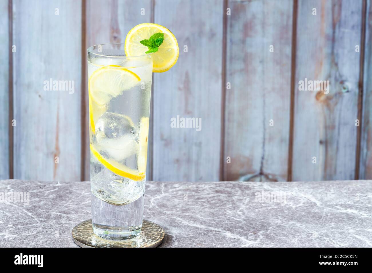 Water with lemon and ice cubes garnished with a slice of lemon and mint ...