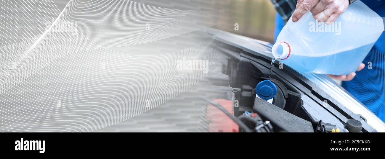 Hands of mechanic pouring blue windshield washer fluid in a car; panoramic banner Stock Photo
