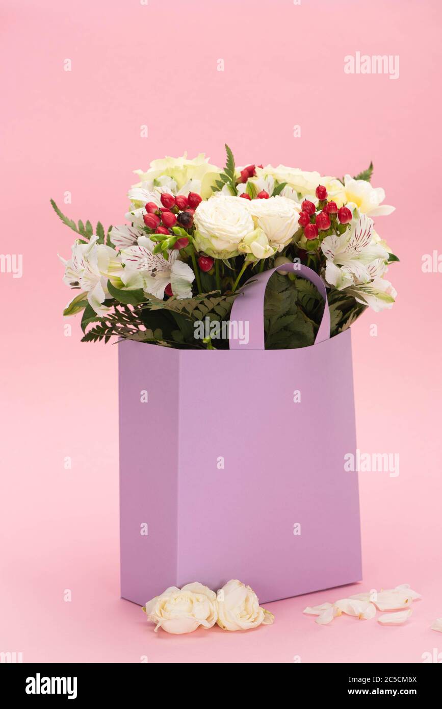 bouquet of flowers in violet paper bag near petals on pink background Stock  Photo - Alamy