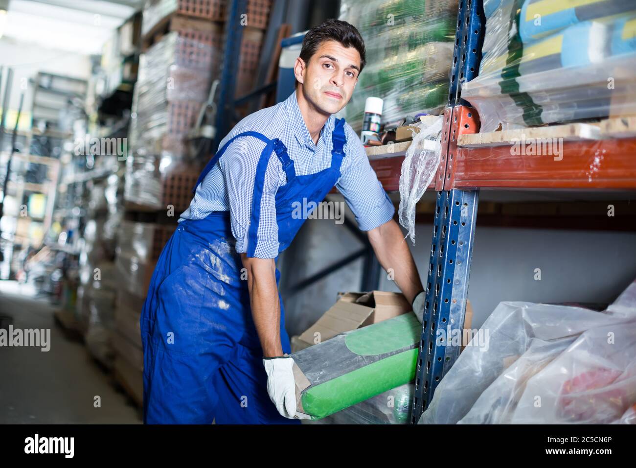 calm male in uniform is choosing cement in the building store room Stock Photo