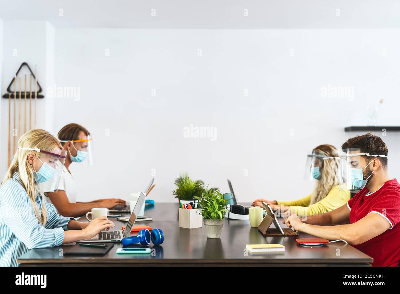 Young people working in co-working creative space wearing surgical mask protection for preventing corona virus spread Stock Photo