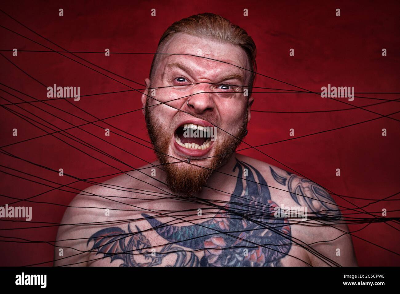 Photo of tangled in black threads bearded man Stock Photo