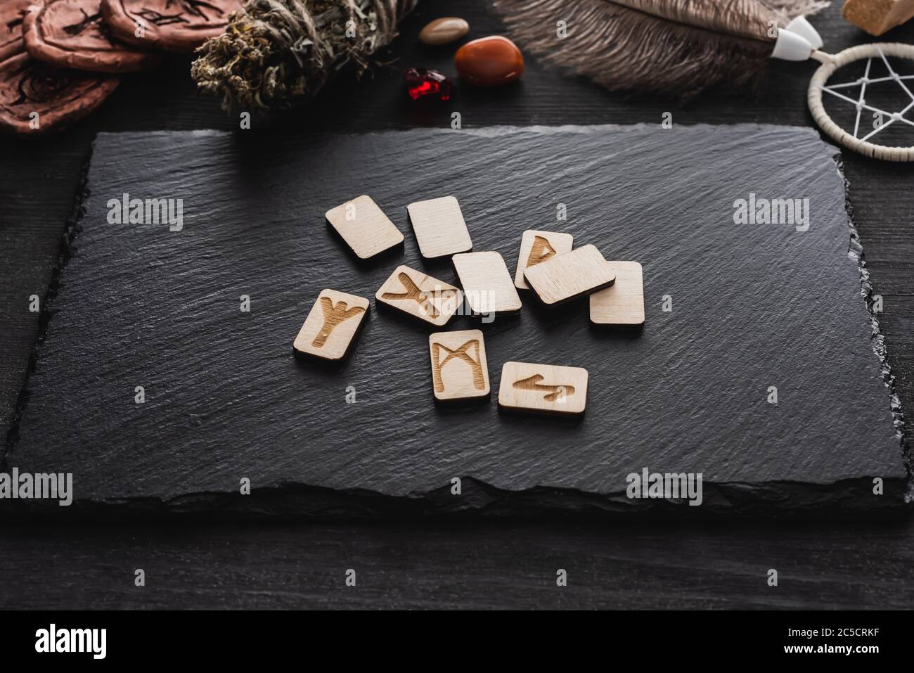 top view of scandinavian runes near stones and dried herb on black ...