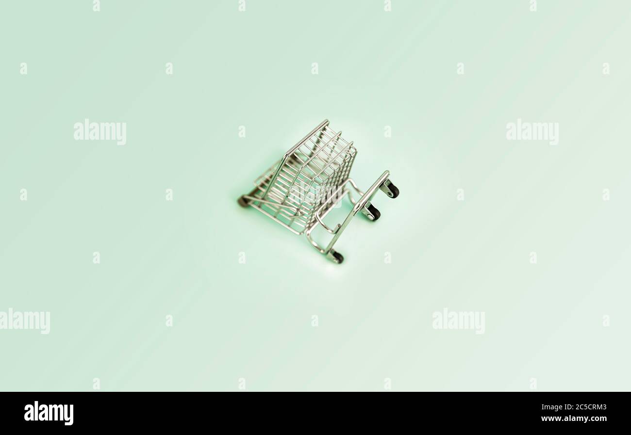 empty shopping cart over colour background, mini metal cart on color background Stock Photo