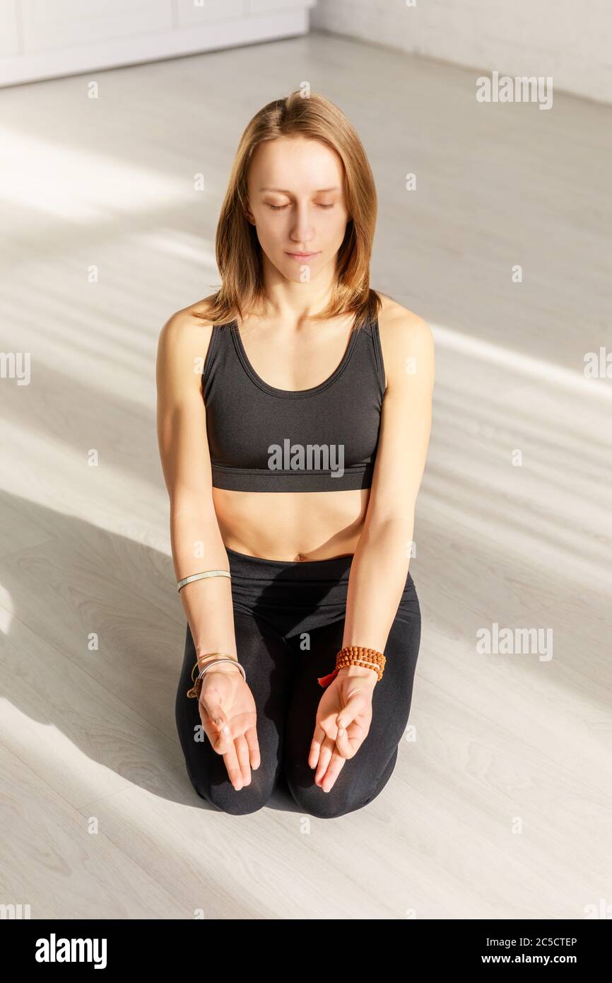 attractive woman with closed eyes meditating while sitting on floor Stock Photo