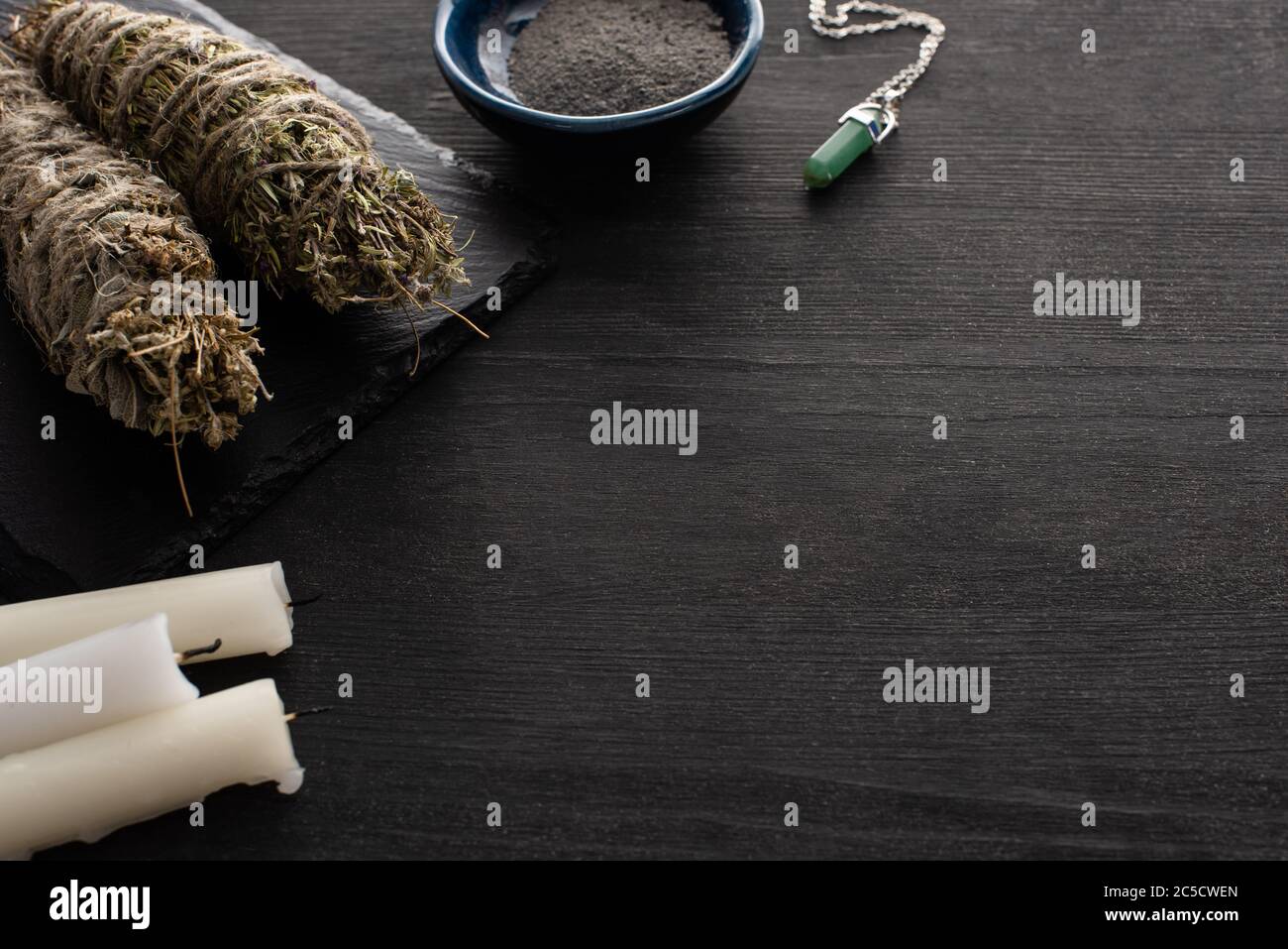 Candles, smudge sticks with crystal and bowl of ash on dark wooden surface Stock Photo