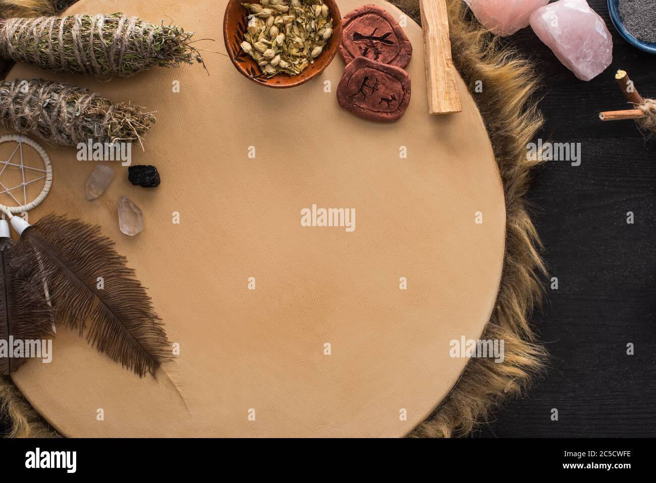Top view of shamanic dreamcatcher, herbs and crystals on tambourine on ...
