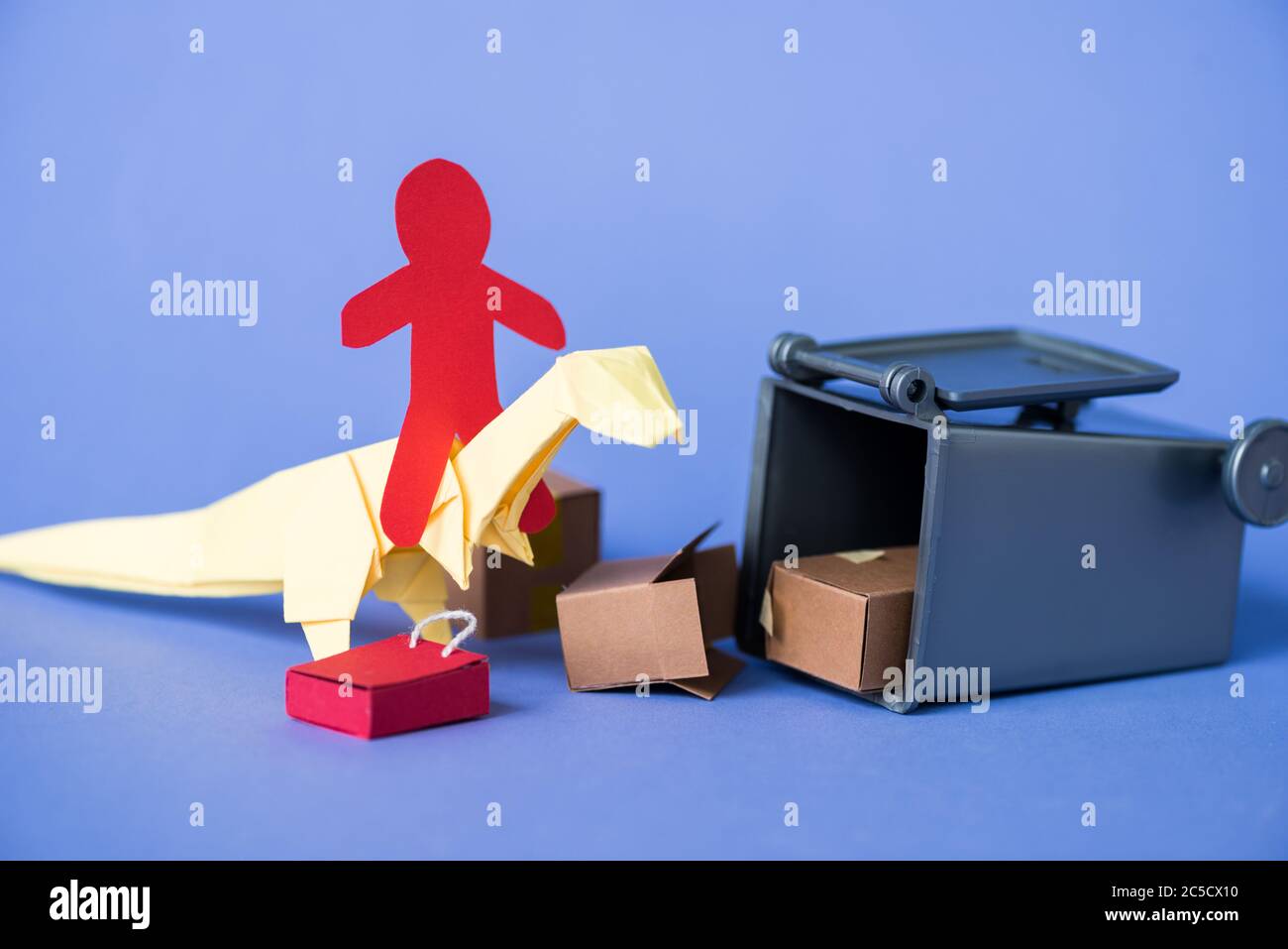 paper human on origami dinosaur near trash can and carton boxes on blue Stock Photo