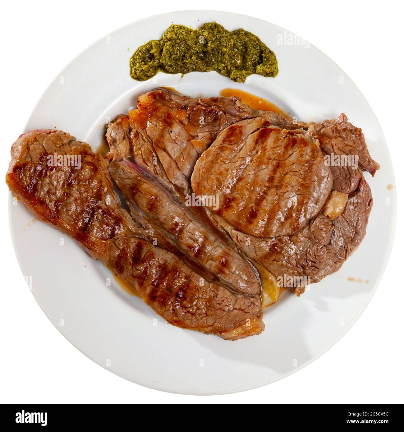 Delicious fried beef entrecote served with pesto sauce. Isolated over