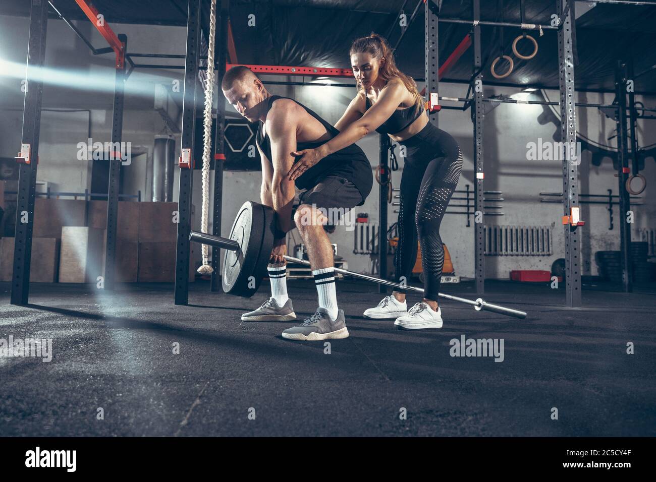 Beautiful young sporty couple training, workout in gym together ...