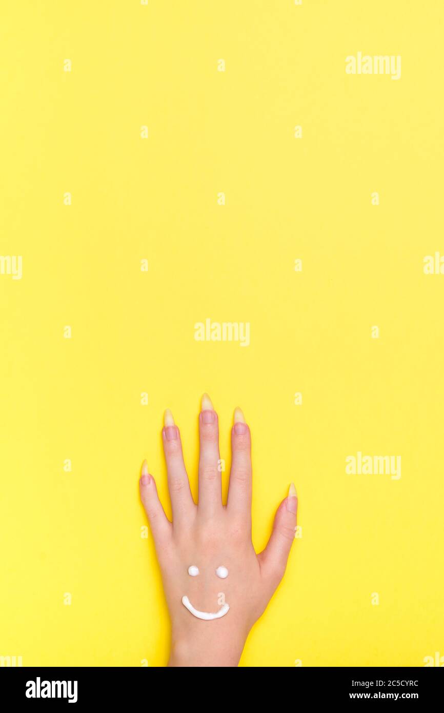 Beauty and health concept of hands. Moisturizing cream for skin care. View from the top is vertical. Girl's hand on a yellow background. Woman's hand Stock Photo