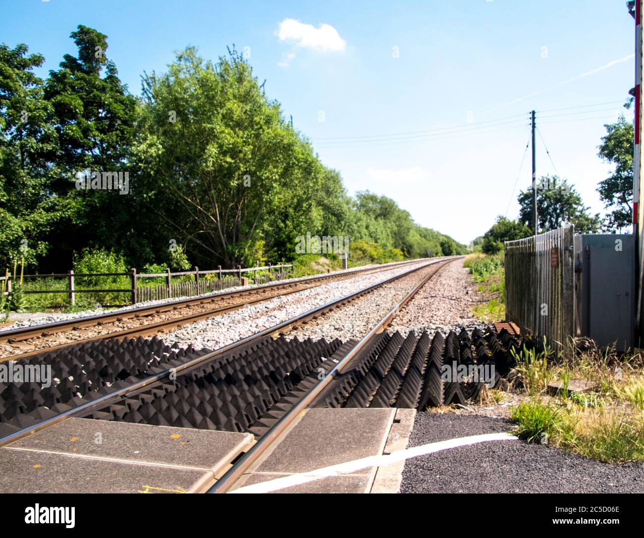 A typical railway line crossing in the United Kingdom, on a dry summer
